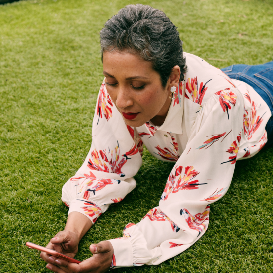 Woman in flower shirt laying in the grass looking for a religious life coach